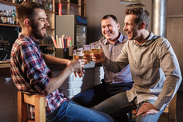 Image showing Happy friends drinking beer at counter in pub