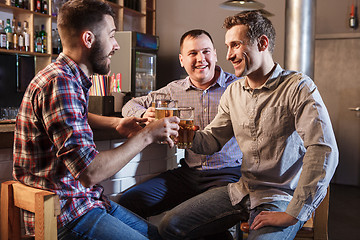 Image showing Happy friends drinking beer at counter in pub