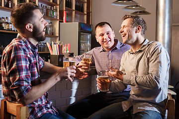 Image showing Happy friends drinking beer at counter in pub