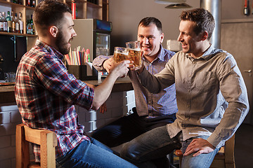 Image showing Happy friends drinking beer at counter in pub