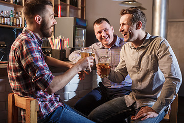 Image showing Happy friends drinking beer at counter in pub