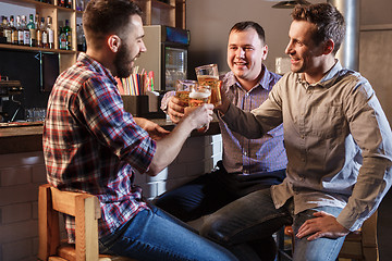 Image showing Happy friends drinking beer at counter in pub