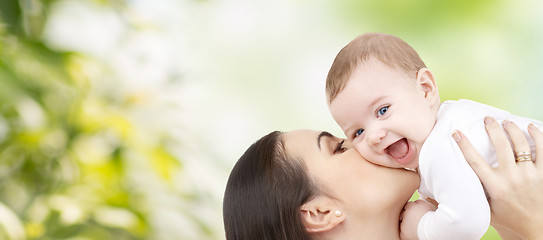 Image showing happy mother kissing baby over green background