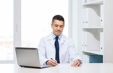 Image showing smiling male doctor with laptop in medical office