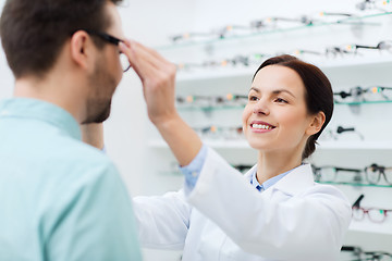 Image showing optician putting on glasses to man at optics store