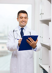 Image showing happy doctor with clipboard in medical office