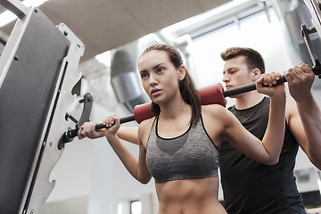 Image showing man and woman with barbell flexing muscles in gym