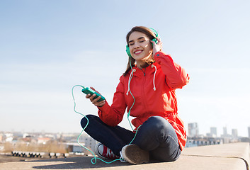 Image showing happy young woman with smartphone and headphones