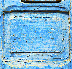 Image showing stripped paint in the blue wood door and rusty nail