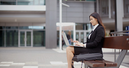Image showing Side view of woman alone with laptop on bench