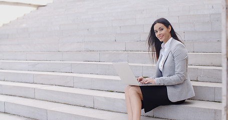 Image showing Smiling woman using laptop on stairs