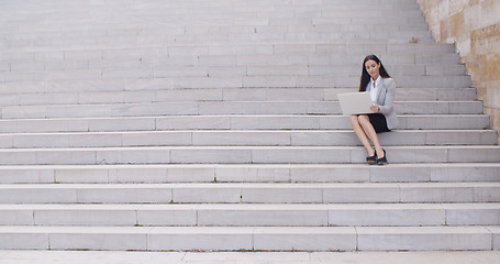 Image showing Business woman with laptop on stairs