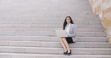 Image showing Business woman with laptop on stairs