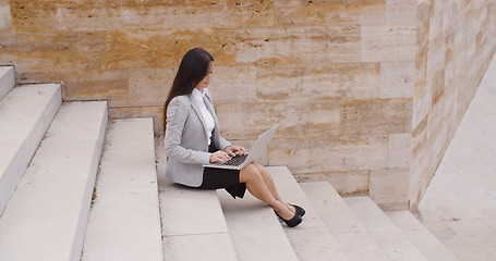 Image showing Side view of woman using laptop on stairs