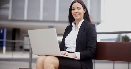 Image showing Smiling female worker with laptop on bench