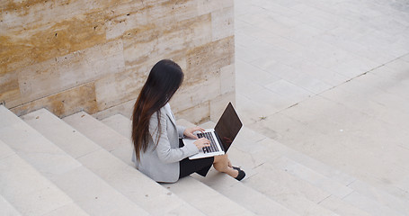 Image showing High angle view of woman on laptop on stairs