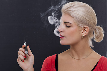 Image showing Stylish blond woman smoking an e-cigarette