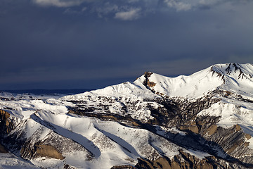 Image showing Winter mountains at sun evening and dark clouds