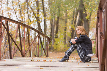 Image showing Sad girl sitting on a bridge in the forest