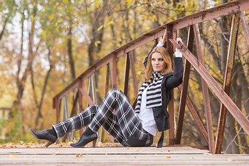 Image showing Happy girl sitting on a bridge in the forest