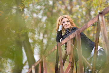 Image showing Young beautiful girl standing on the bridge and happily leaning on the railing