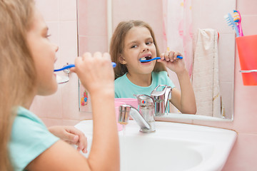 Image showing Six year old girl cleans the upper lateral teeth look in the mirror in the bathroom