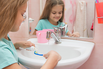 Image showing Girl before cleaning teeth squeezing toothpaste out of a tube on toothbrush