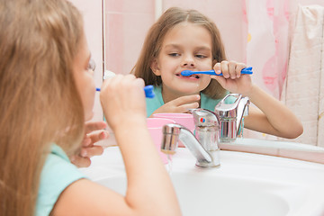 Image showing Six year old girl having fun brushing his teeth look in the mirror in the bathroom