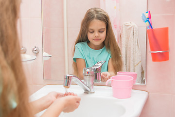 Image showing  Girl pours her hands tap water in the bathroom