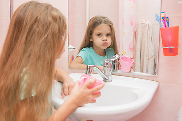 Image showing Girl rinse your mouth in the bathroom and look in the frame