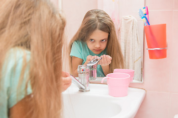 Image showing The girl washing up looked in the mirror in the bathroom