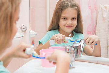 Image showing Six year old girl squeezes the toothpaste from a tube on toothbrush