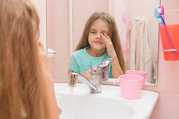 Image showing Girl wet hand wipes the sleep from his eyes in the bathroom