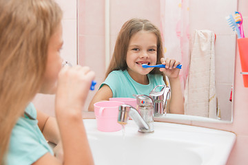 Image showing Six year old girl brushing the front teeth with a smile and looked into the frame