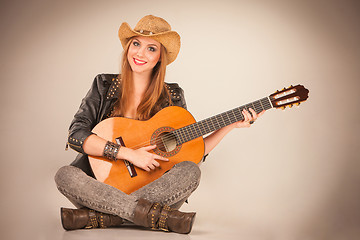 Image showing The beautiful girl in a cowboy\'s hat and acoustic guitar.
