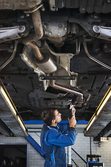 Image showing Young mechanic repairing the exhaust of a car