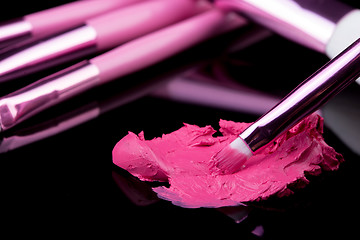 Image showing lipstick with a brush make-up on black 