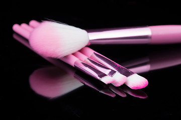 Image showing pink make-up brushes isolated on black background.