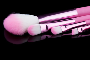 Image showing pink make-up brushes isolated on black background.