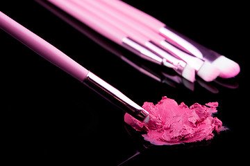 Image showing lipstick with a brush make-up on black 