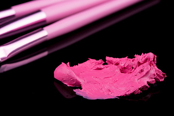 Image showing lipstick with a brush make-up on black 