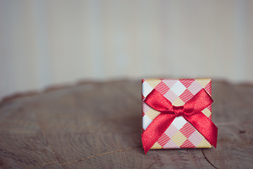 Image showing Gift box with red bow on wood background