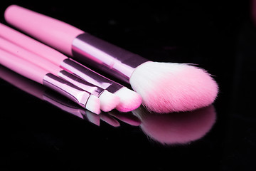 Image showing pink make-up brushes isolated on black background.