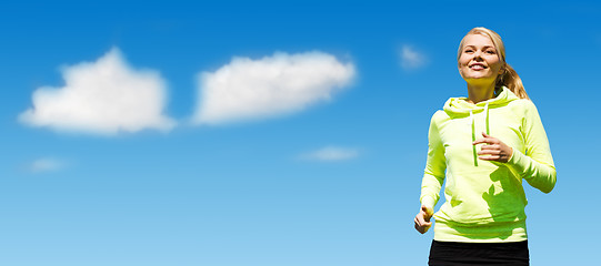 Image showing woman jogging over blue sky and clouds background