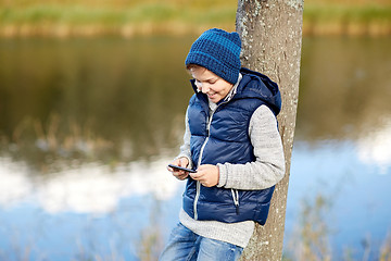 Image showing happy boy playing game on smartphone outdoors