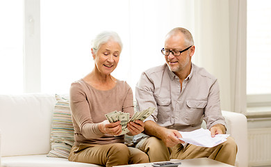 Image showing senior couple with money and calculator at home