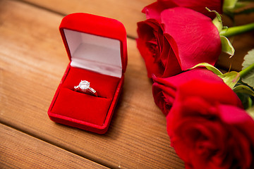 Image showing close up of diamond engagement ring and red roses