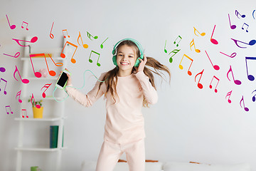 Image showing girl jumping on bed with smartphone and headphones