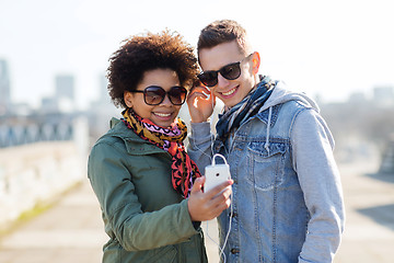 Image showing smiling couple with smartphone and earphones