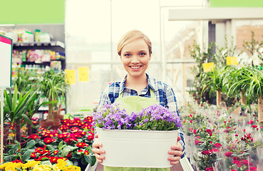 Image showing happy woman holding flowers in greenhouse